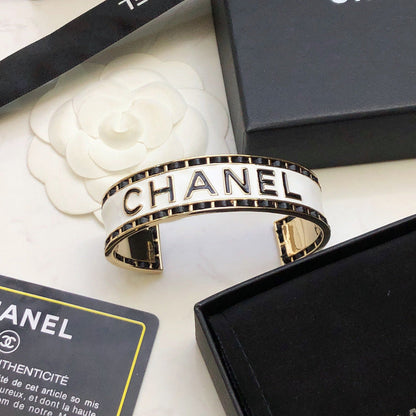 CHANEL 26S CHANEL LOGO ENAMEL CUFF BRACELET WITH BLACK TRIM IN GOLD METAL 630835
