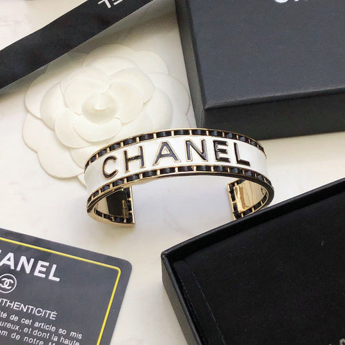 CHANEL 26S CHANEL LOGO ENAMEL CUFF BRACELET WITH BLACK TRIM IN GOLD METAL 630835